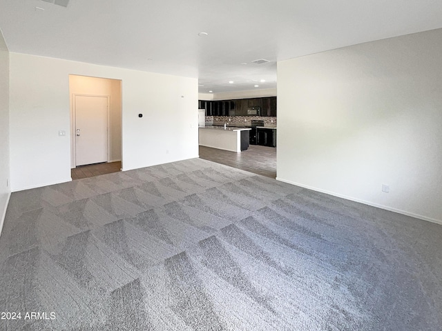 unfurnished living room with visible vents, dark colored carpet, and recessed lighting