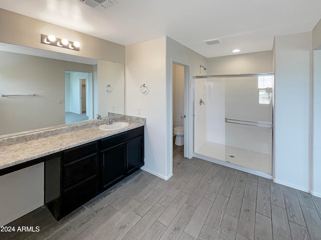 bathroom with an enclosed shower, toilet, hardwood / wood-style floors, and vanity