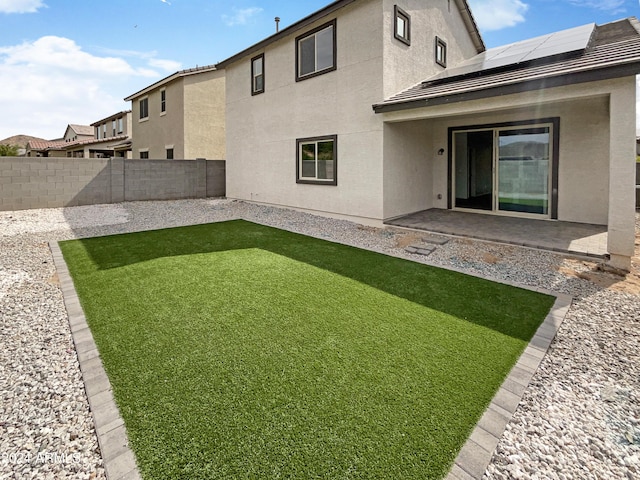 rear view of house with a patio area, stucco siding, a fenced backyard, and solar panels