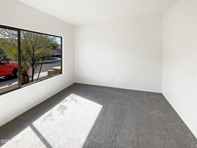 empty room with dark carpet and baseboards