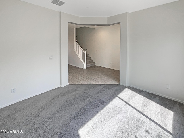 carpeted spare room with visible vents, stairway, and baseboards