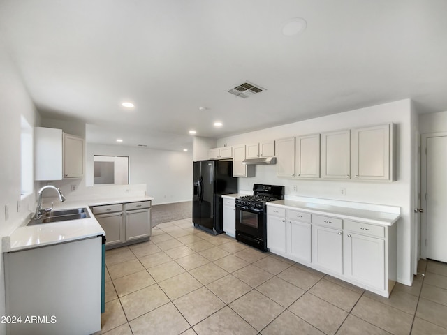 kitchen with white cabinets, sink, light tile patterned floors, and black appliances