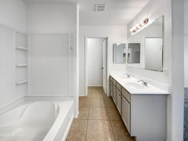 bathroom with tile patterned floors, a tub, and vanity