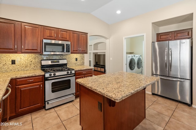 12712 W Milton Dr, Peoria, AZ 85383 - kitchen with stainless steel appliances, washing machine and dryer, lofted ceiling, light tile patterned floors, and tasteful backsplash