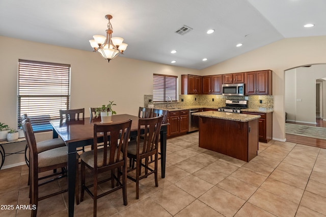 12712 W Milton Dr, Peoria, AZ 85383 - kitchen with appliances with stainless steel finishes, lofted ceiling, decorative backsplash, a chandelier, and a center island