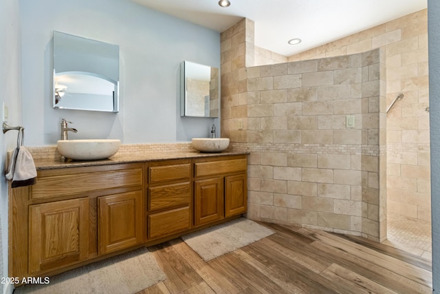 bathroom featuring hardwood / wood-style floors, vanity, and a tile shower