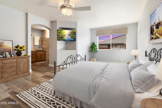 bedroom with light hardwood / wood-style floors, ensuite bathroom, and ceiling fan