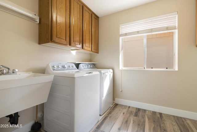 laundry area with sink, light wood-type flooring, cabinets, and independent washer and dryer