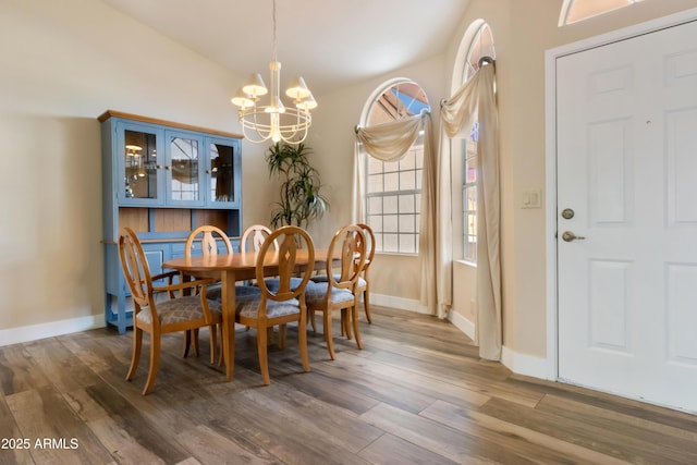 dining space featuring dark hardwood / wood-style floors, a notable chandelier, and vaulted ceiling