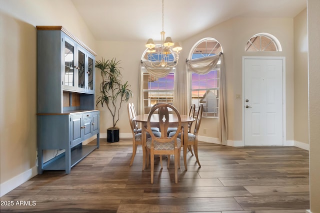 dining area with dark wood-type flooring, a chandelier, and vaulted ceiling