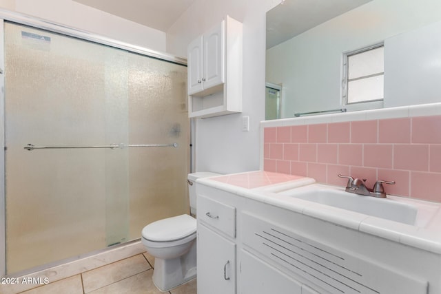 bathroom featuring vanity, backsplash, tile patterned flooring, toilet, and a shower with shower door