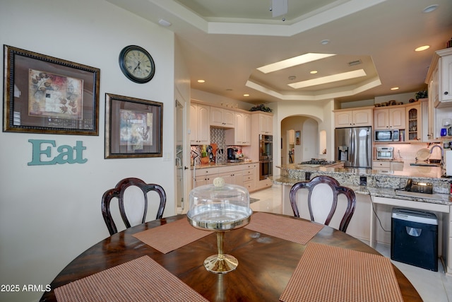 dining area featuring arched walkways, recessed lighting, and a raised ceiling