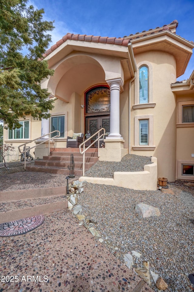 view of exterior entry with a porch and stucco siding