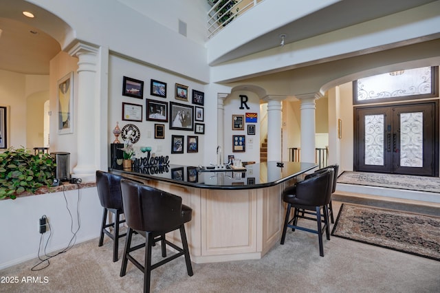 bar with decorative columns, arched walkways, and light carpet