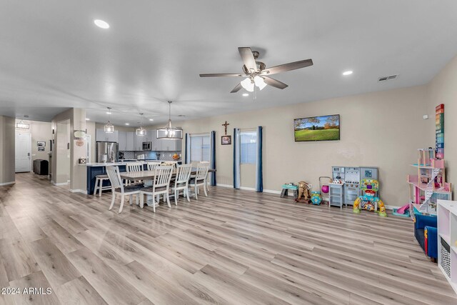 dining space with ceiling fan and light wood-type flooring