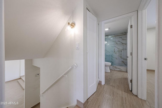 corridor with an upstairs landing and light wood-style floors