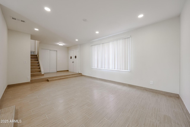 empty room featuring light wood-type flooring, stairs, visible vents, and recessed lighting