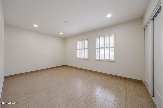 spare room with recessed lighting, light wood-style flooring, and baseboards