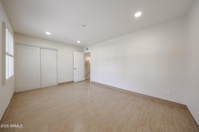 unfurnished bedroom featuring light wood-style flooring, baseboards, a closet, and recessed lighting