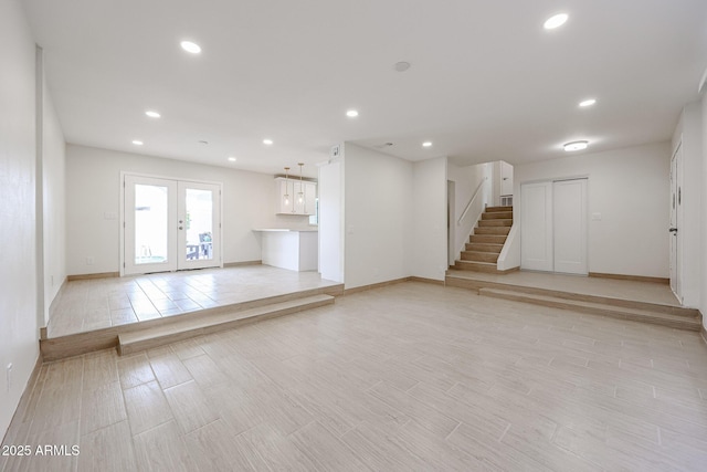 unfurnished living room with french doors, recessed lighting, stairway, wood tiled floor, and baseboards