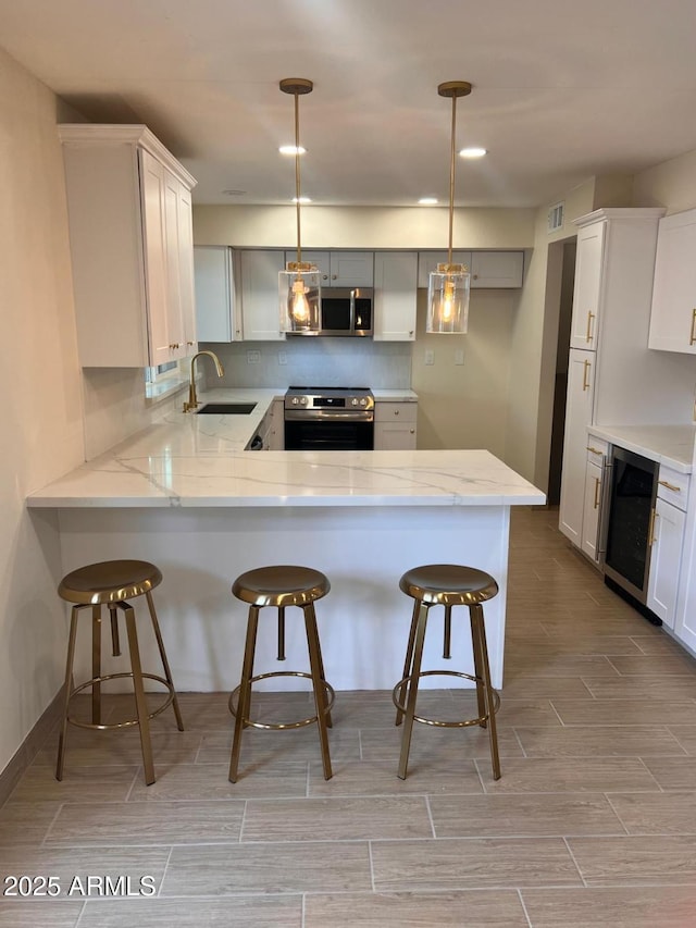 kitchen with wine cooler, a peninsula, wood tiled floor, stainless steel appliances, and a sink