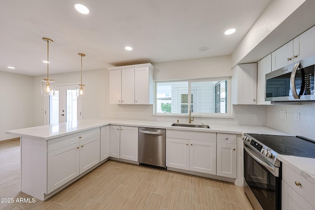 kitchen with tasteful backsplash, appliances with stainless steel finishes, a peninsula, white cabinetry, and a sink