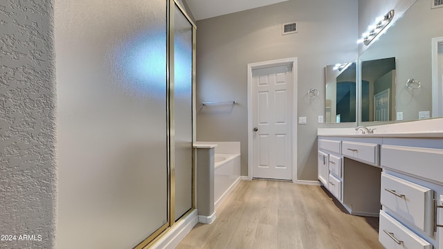 bathroom featuring plus walk in shower, vanity, and hardwood / wood-style flooring