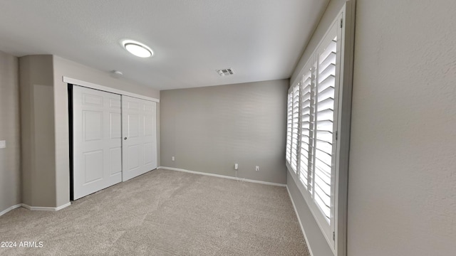 unfurnished bedroom featuring light carpet and a closet