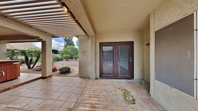 entrance to property featuring a hot tub, a patio area, and french doors