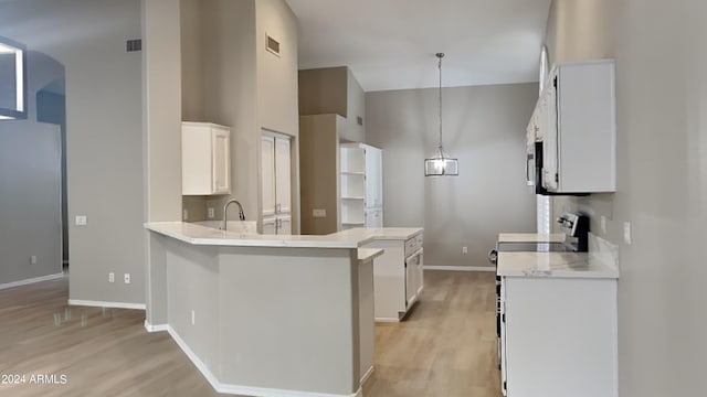 kitchen featuring kitchen peninsula, stove, decorative light fixtures, light hardwood / wood-style floors, and white cabinetry