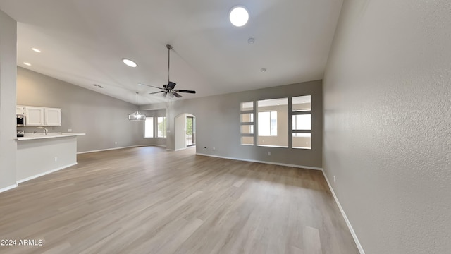 unfurnished living room featuring light wood-type flooring, high vaulted ceiling, ceiling fan, and sink