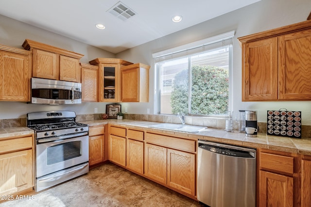 kitchen with appliances with stainless steel finishes, sink, and tile countertops