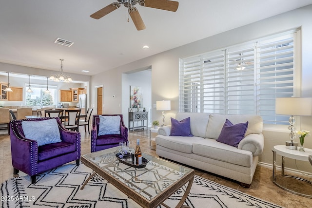 living room with ceiling fan with notable chandelier