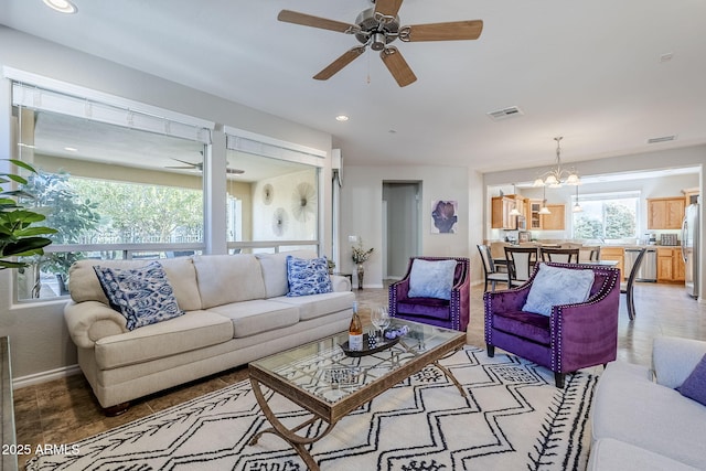 living room with ceiling fan with notable chandelier