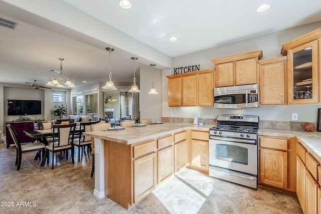 kitchen with an inviting chandelier, appliances with stainless steel finishes, decorative light fixtures, and light brown cabinetry