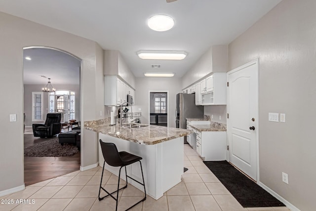 2714 N 63rd St, Mesa, AZ 85215 - kitchen with white cabinetry, light tile patterned flooring, kitchen peninsula, and light stone counters