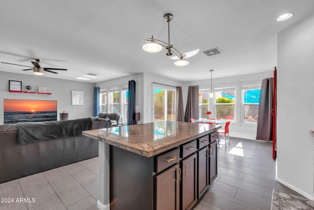 10847 E Forge Cir, Mesa, AZ 85208 - kitchen with baseboards, a center island, decorative light fixtures, and light stone counters