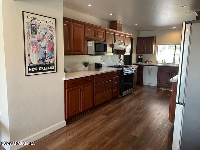 kitchen featuring dark hardwood / wood-style flooring, backsplash, and appliances with stainless steel finishes