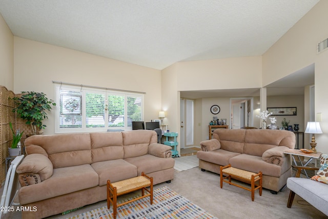 living area featuring visible vents, light colored carpet, and a textured ceiling