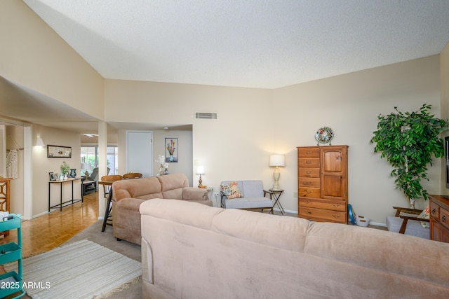 living area featuring baseboards, visible vents, and a textured ceiling