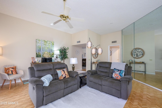 living room featuring visible vents, a textured ceiling, baseboards, and a ceiling fan