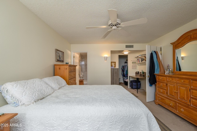 bedroom with a spacious closet, visible vents, light carpet, a closet, and a textured ceiling