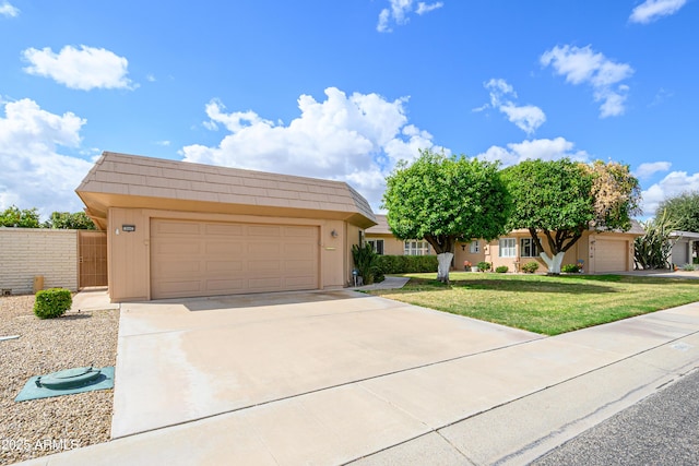 view of front facade featuring concrete driveway, a garage, a front yard, and mansard roof