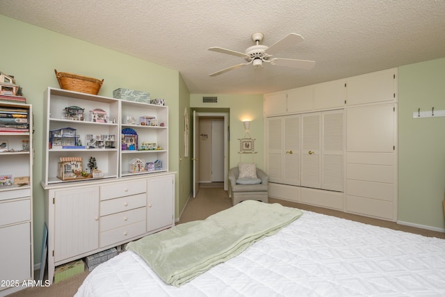 bedroom featuring a closet, visible vents, a textured ceiling, and ceiling fan