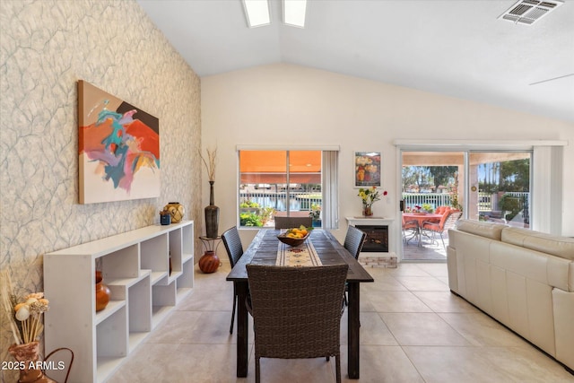 dining area with plenty of natural light, visible vents, vaulted ceiling, and light tile patterned flooring