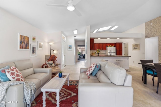 living area featuring light tile patterned floors, baseboards, vaulted ceiling, and a ceiling fan