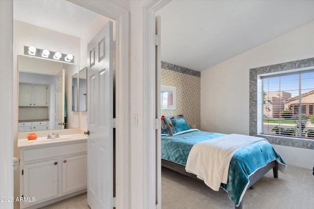 bedroom featuring light carpet, wallpapered walls, and a sink