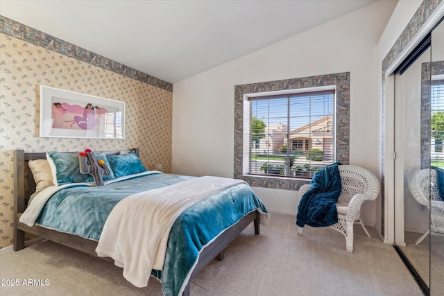 bedroom with lofted ceiling, a closet, light carpet, and wallpapered walls