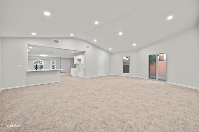 unfurnished living room featuring vaulted ceiling and light colored carpet