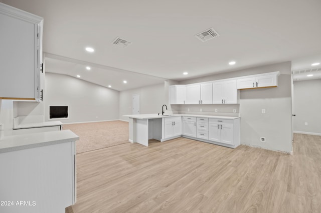 kitchen featuring white cabinetry, kitchen peninsula, sink, and light hardwood / wood-style floors